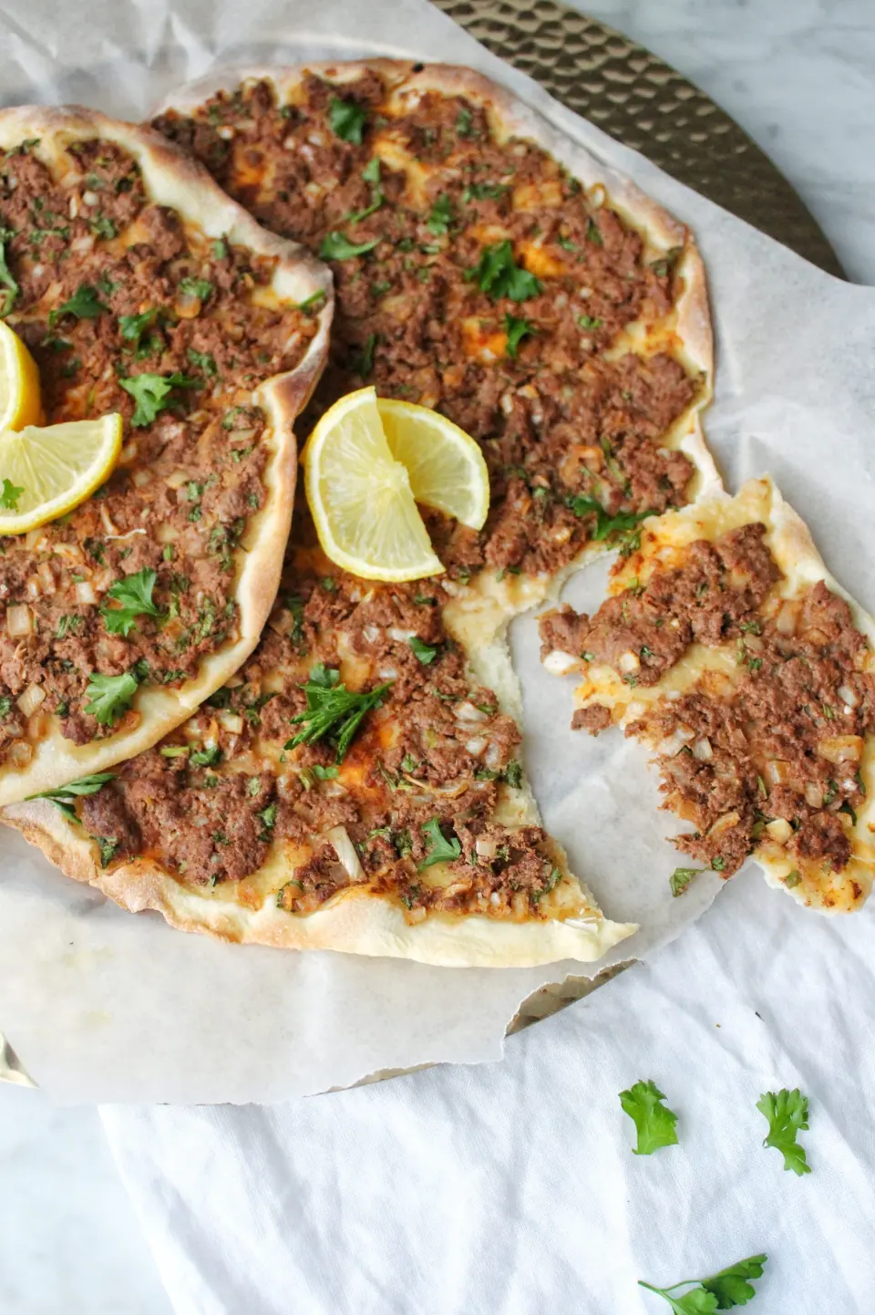 Flatbreads spread with spiced beef, with lemon on the side